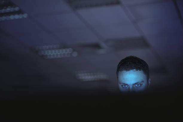 computer hacker working on laptop late at night in office