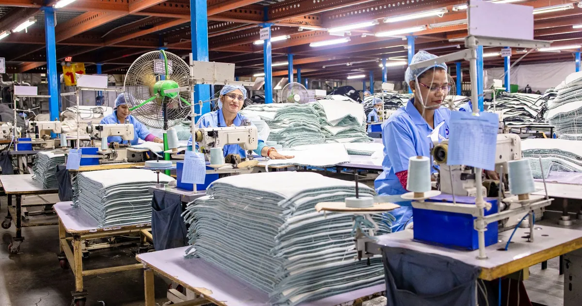 Workers in a textile factory operating sewing machines and organizing fabric.