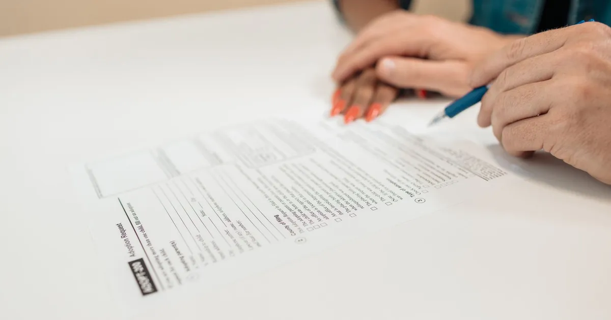Close-up of hands signing adoption papers in an office environment, symbolizing family and legal process.