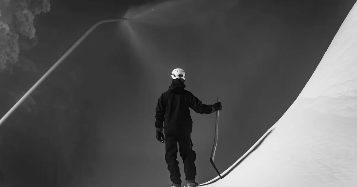 A black and white photo of a person making snow at night in Falun, Sweden.