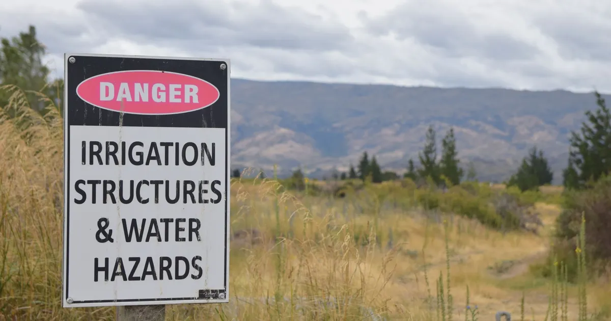 Danger sign warning about irrigation structures and water hazards in rural Otago, New Zealand.
