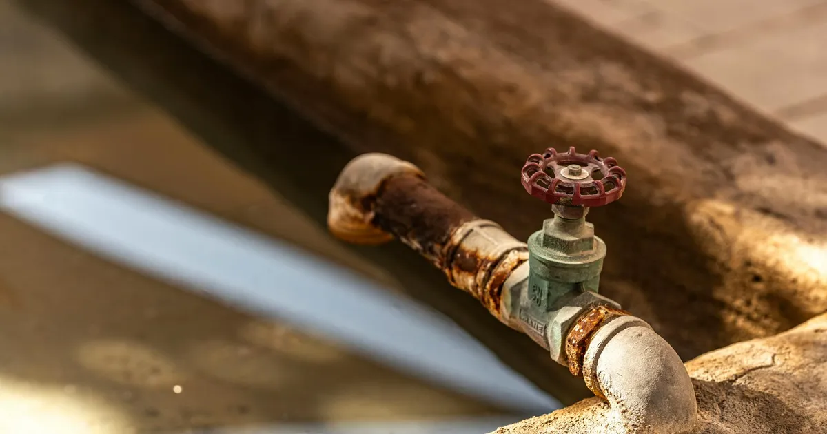 Close-up of a rusty water valve with reflections in a Dubai setting, highlighting decay and water themes.