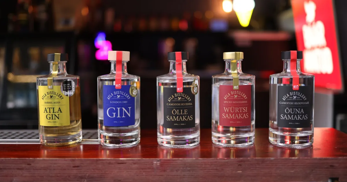A close-up look at five artisanal gin bottles displayed on a wooden bar counter indoors.