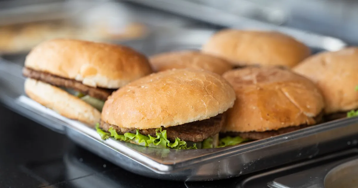 Appetizing close-up of freshly made burgers on a stainless steel tray, ready to serve.