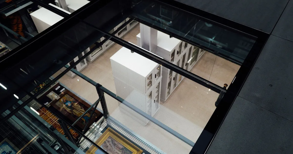 A unique aerial shot of an art storage area viewed through a glass ceiling, showcasing paintings and art panels.
