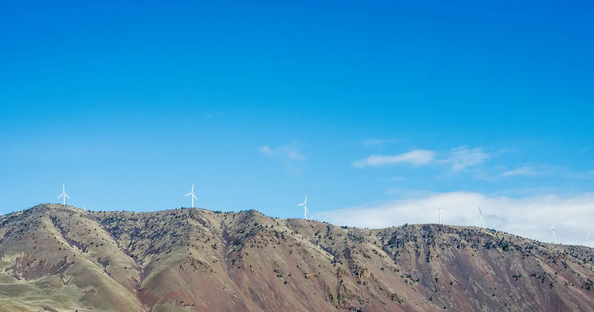 Wind turbines on scenic hills in Portland, Oregon, under a clear blue sky, showcasing renewable energy.