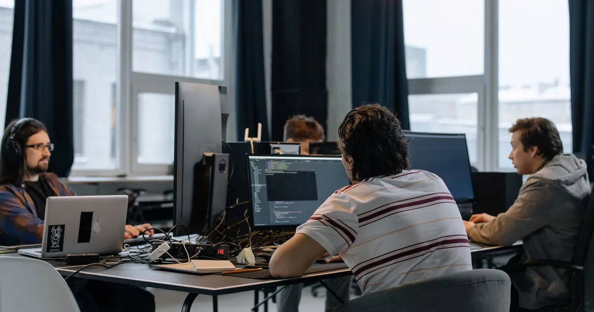Team of developers working together on computers in a modern tech office.