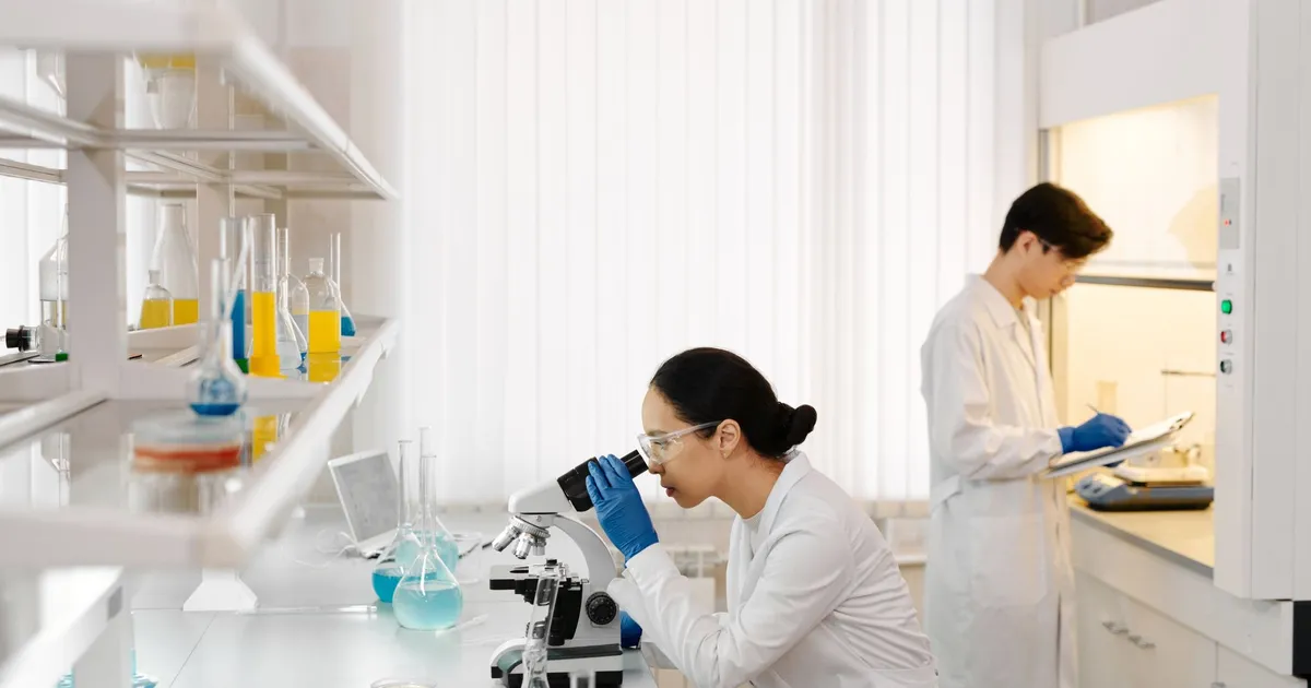 Two scientists working in a well-equipped laboratory with microscopes and test tubes.