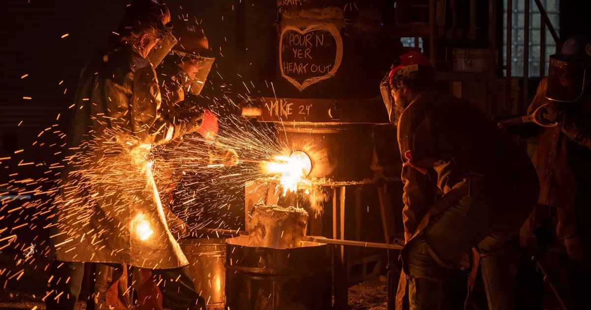 Industrial workers pouring molten metal with sparks flying in Milwaukee workshop.
