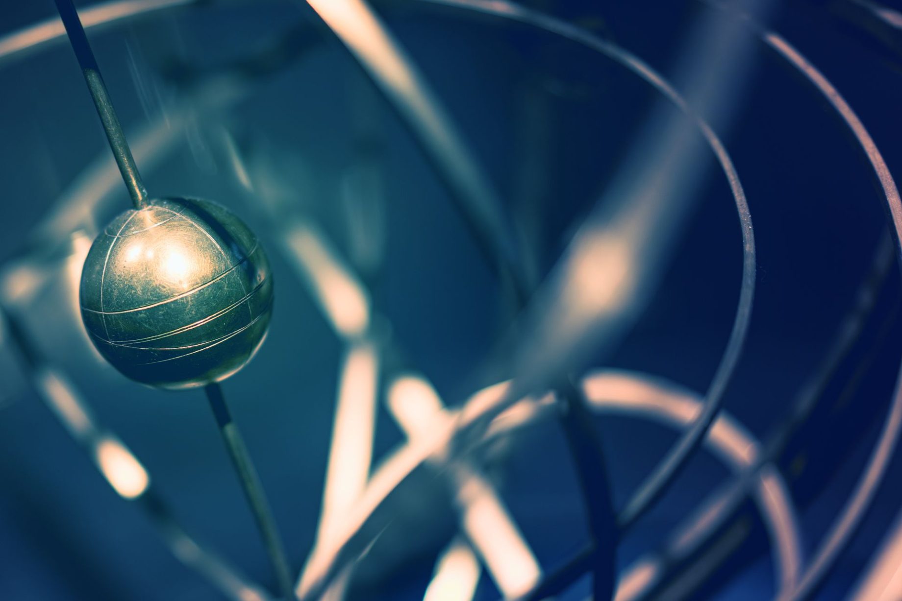 Abstract metallic sphere surrounded by circular ring structures, representing quantum computing, advanced technology, or cybersecurity concepts.
