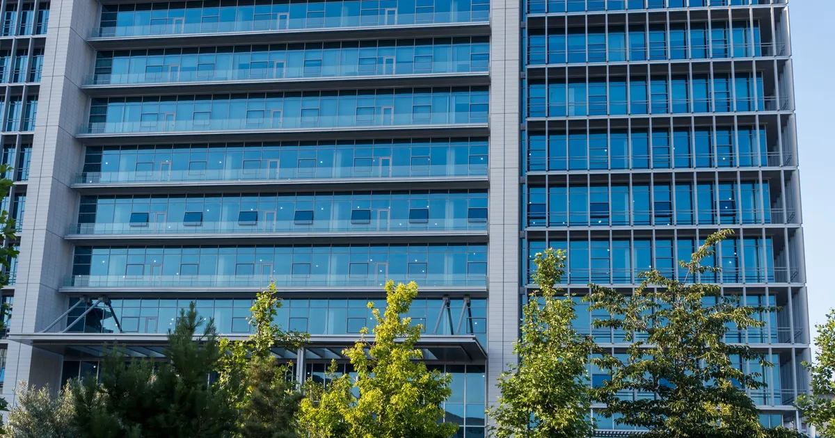 Glass facade skyscraper with trees in downtown urban scene, perfect for business and architecture themes.