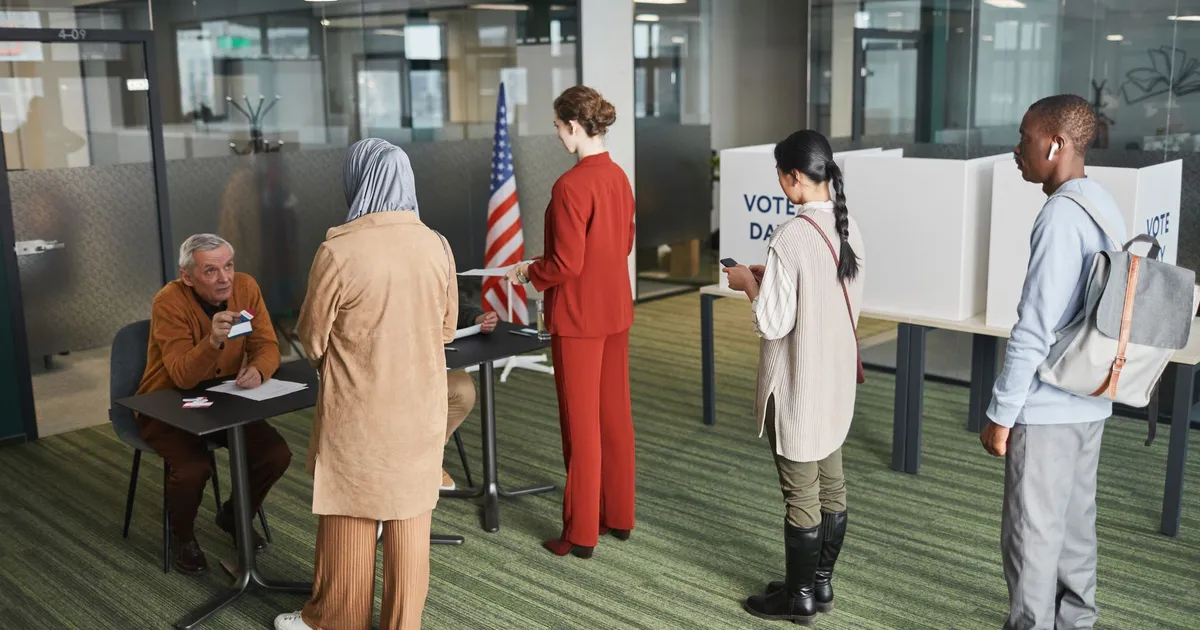 Diverse group of voters lining up at an indoor polling station on election day.
