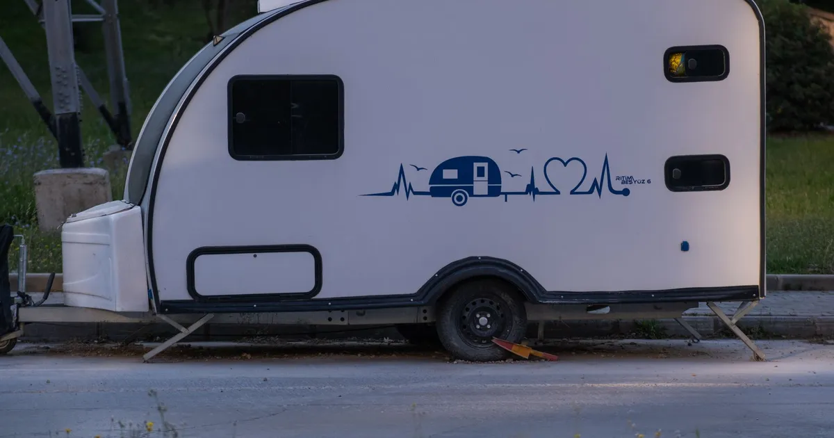 Side view of a modern teardrop caravan parked in İzmir, Türkiye on a quiet street.