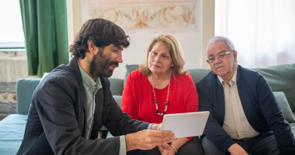 A financial advisor discussing investment options with an elderly couple in a cozy living room.