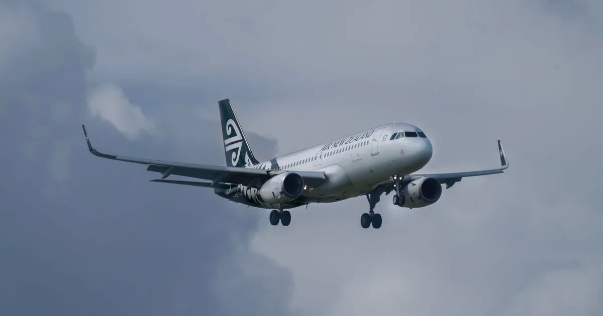 Air New Zealand aircraft flying amidst cloudy sky, showcasing aviation travel.