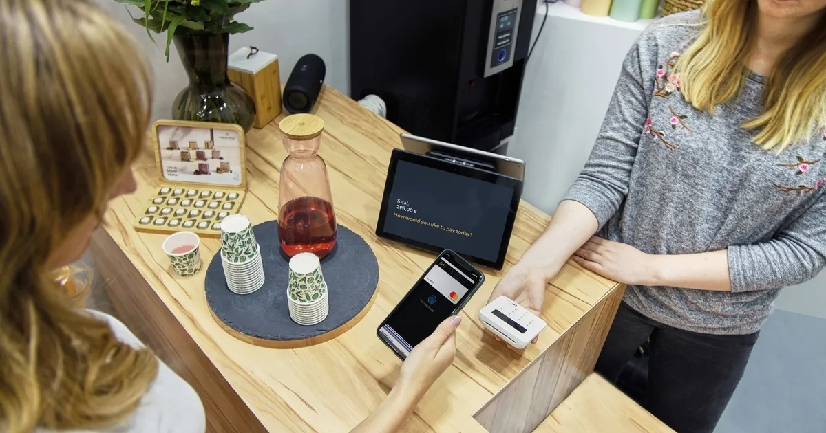 A woman makes a contactless payment at a stylish Berlin café, emphasizing technology and modern retail.
