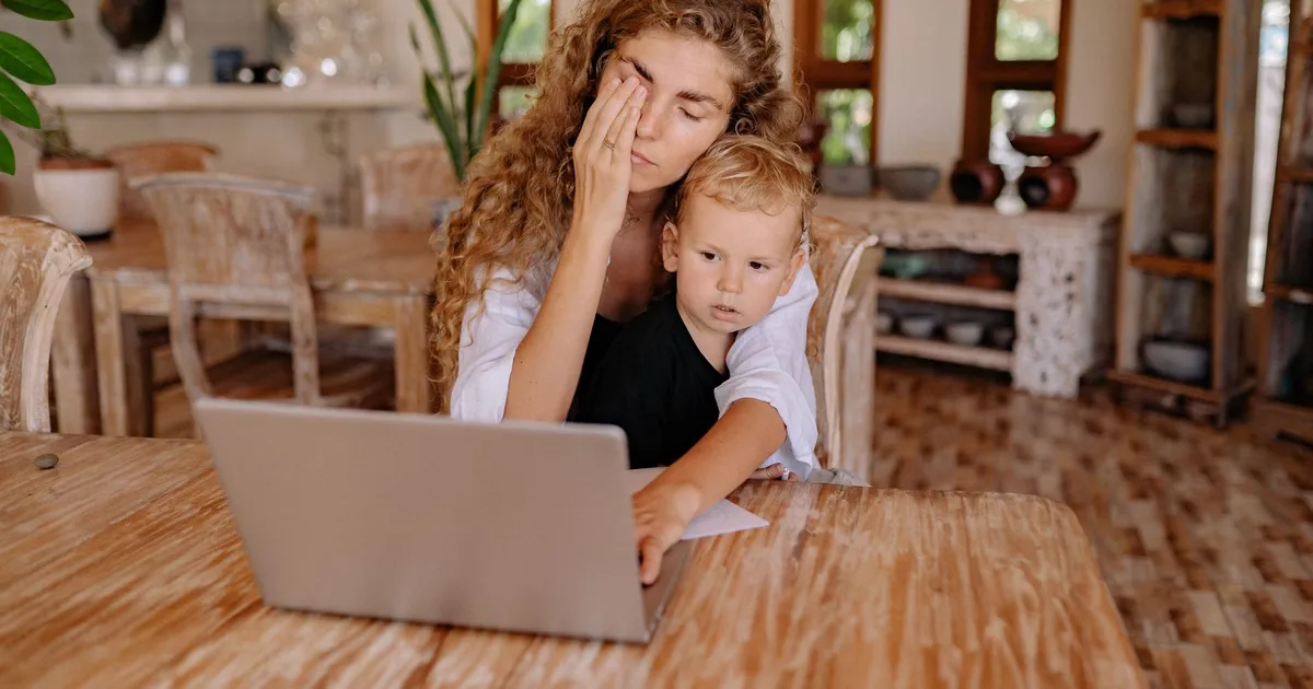 Woman multitasking while working from home with child. Relaxed ambiance.