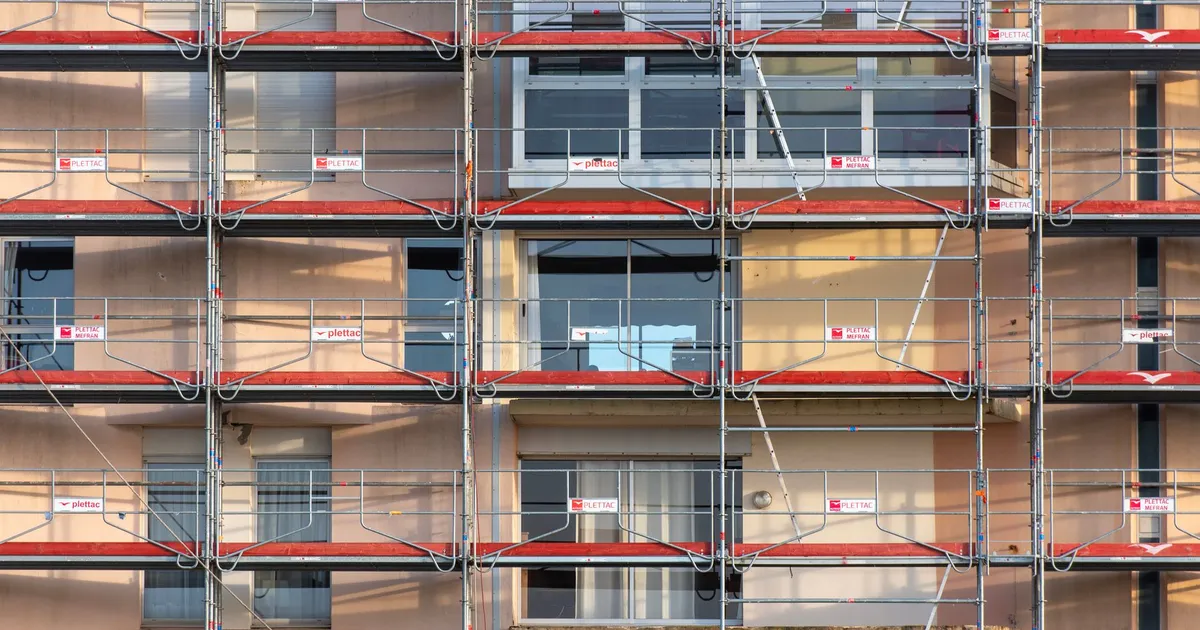 Scaffolding covers an urban building facade, capturing a construction site in detail.