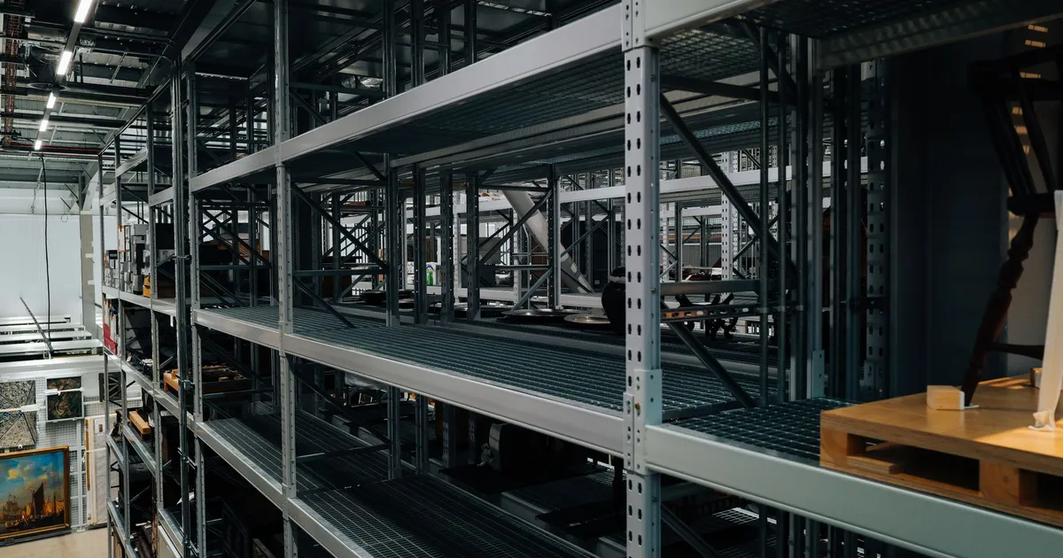 Empty metal storage racks in a spacious industrial warehouse setting.