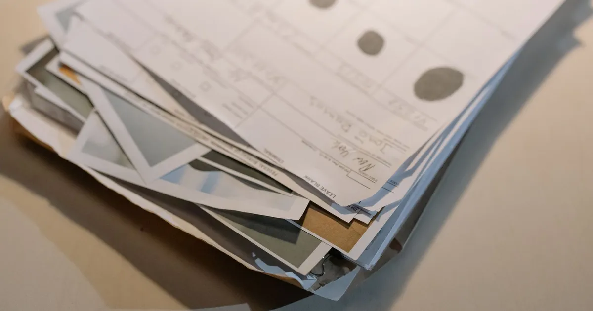 Close-up view of a stack of various papers and documents on a desk surface.