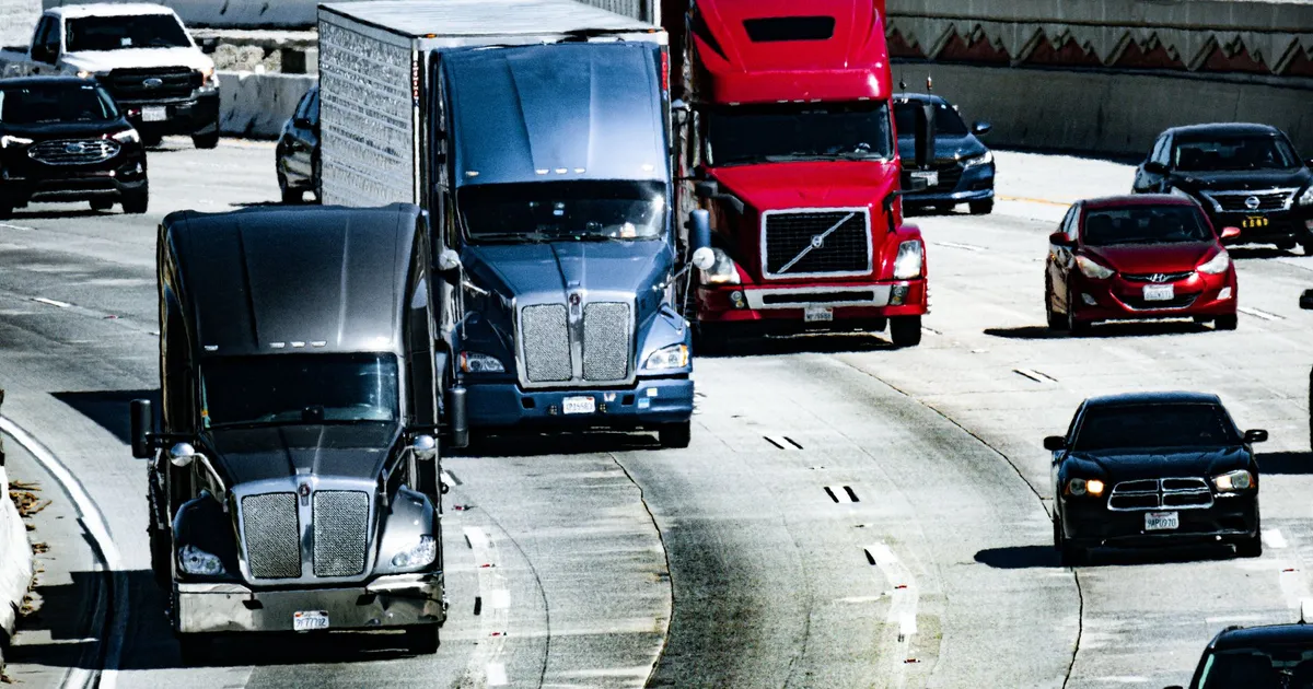 Trucks and cars traveling on a congested city highway during the day.