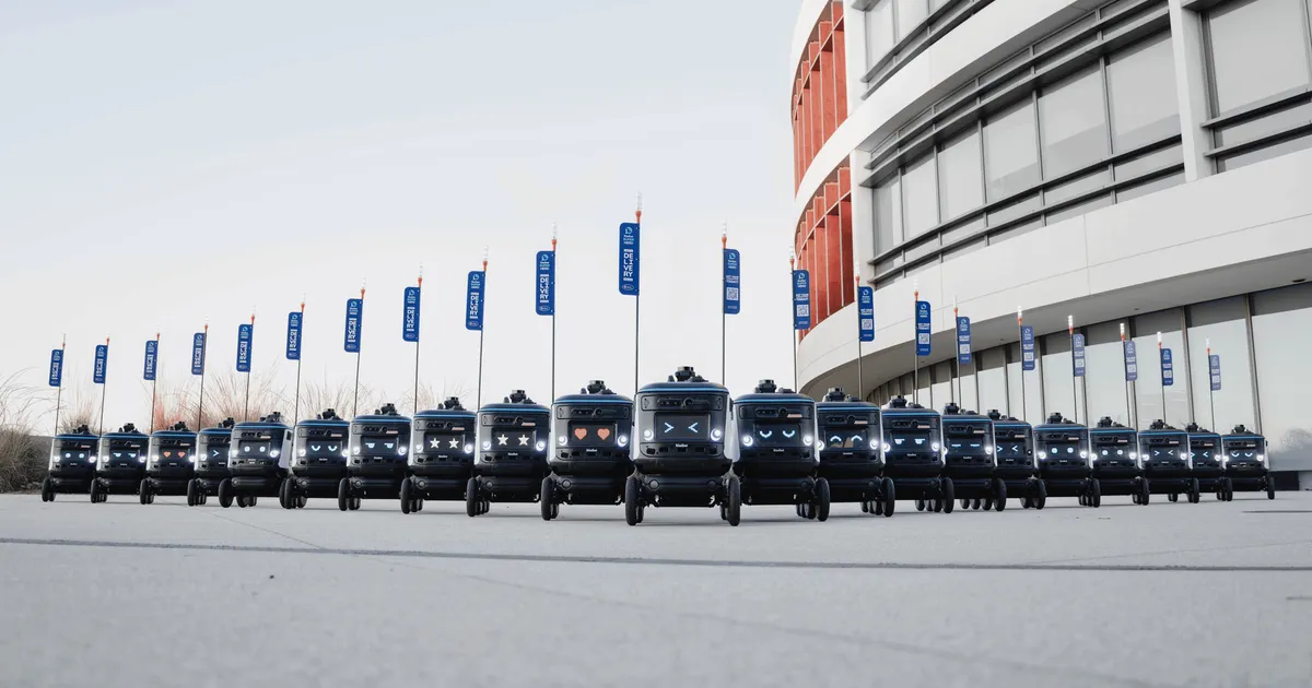 A fleet of delivery robots aligned outside a modern building, illustrating futuristic technology.