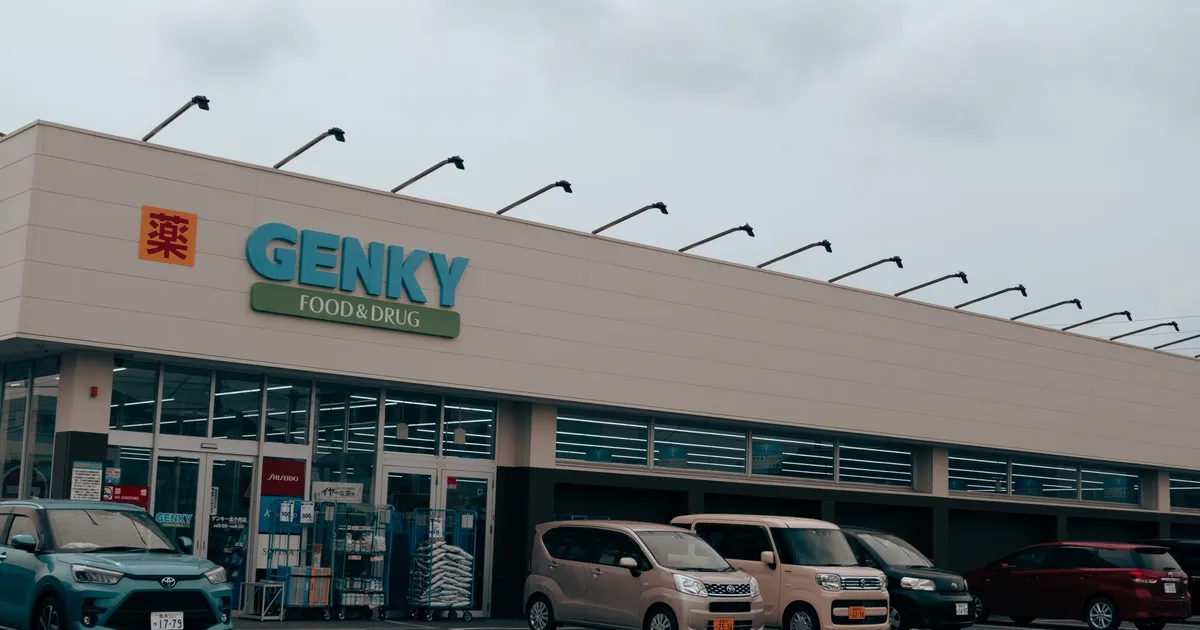 Exterior view of Genky Food & Drug store with parked cars, showcasing urban retail.