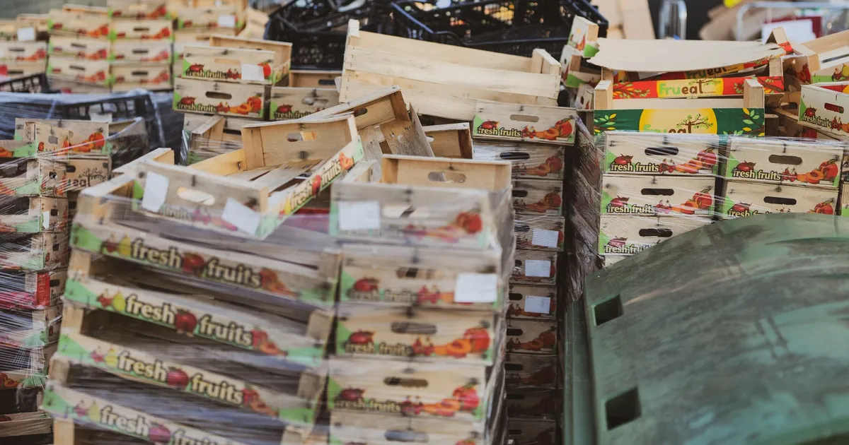Piles of wooden fruit boxes in an outdoor market area, ideal for food or recycling themes.