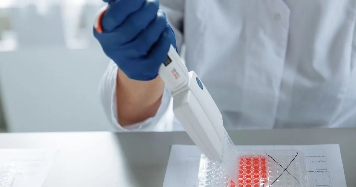 Close-up of a scientist using a pipette in a lab with a focus on sterile procedures.