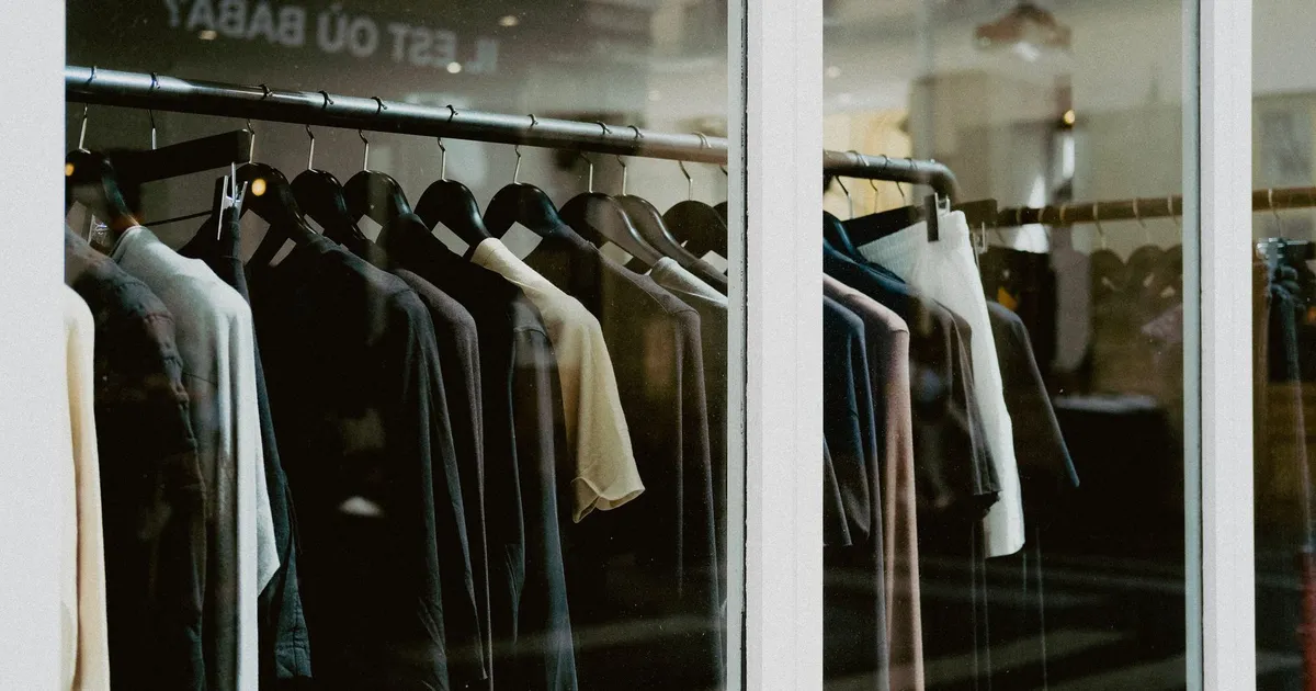 Close-up of clothing on hangers inside a fashion store window.