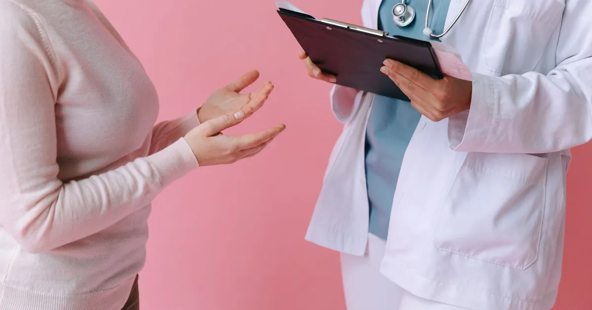Close-up of a patient consulting a doctor with a clipboard in a medical setting.