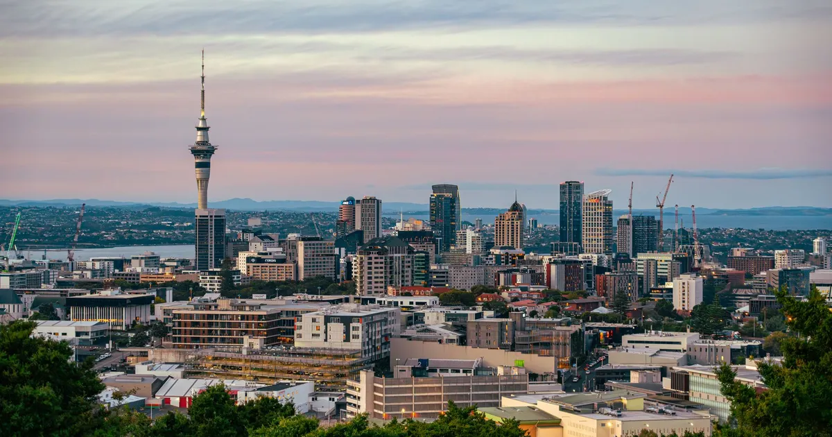 Captivating view of Auckland's skyline at dusk featuring the iconic Sky Tower under a colorful sky.