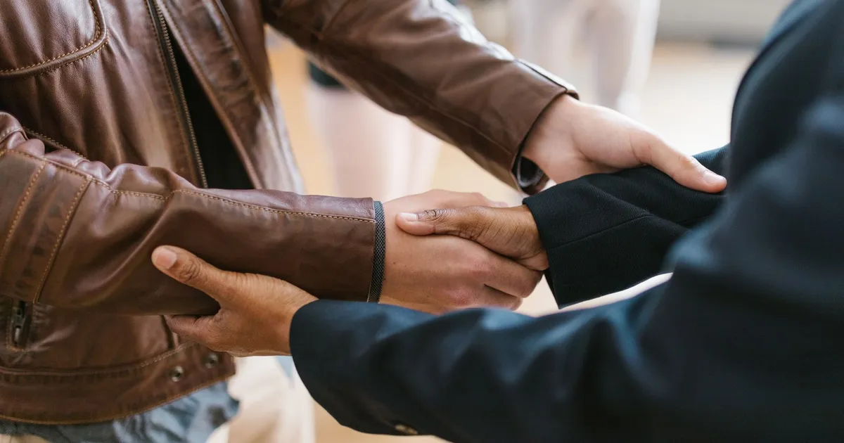 Two business professionals shaking hands, symbolizing teamwork and collaboration indoors.