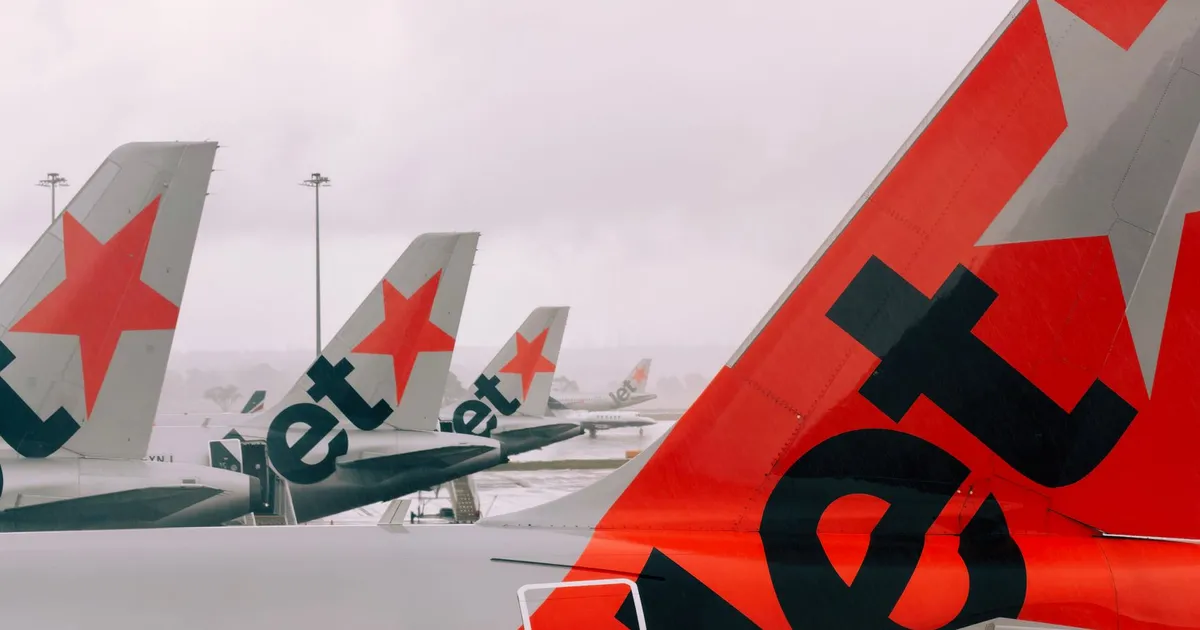 Jetstar planes lined up at Melbourne Airport on a cloudy day, showcasing airline fleet.