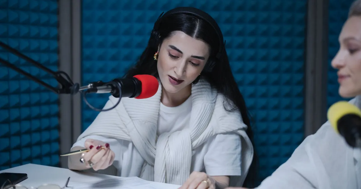 Two women hosting a radio show, using professional microphones in a soundproof studio.