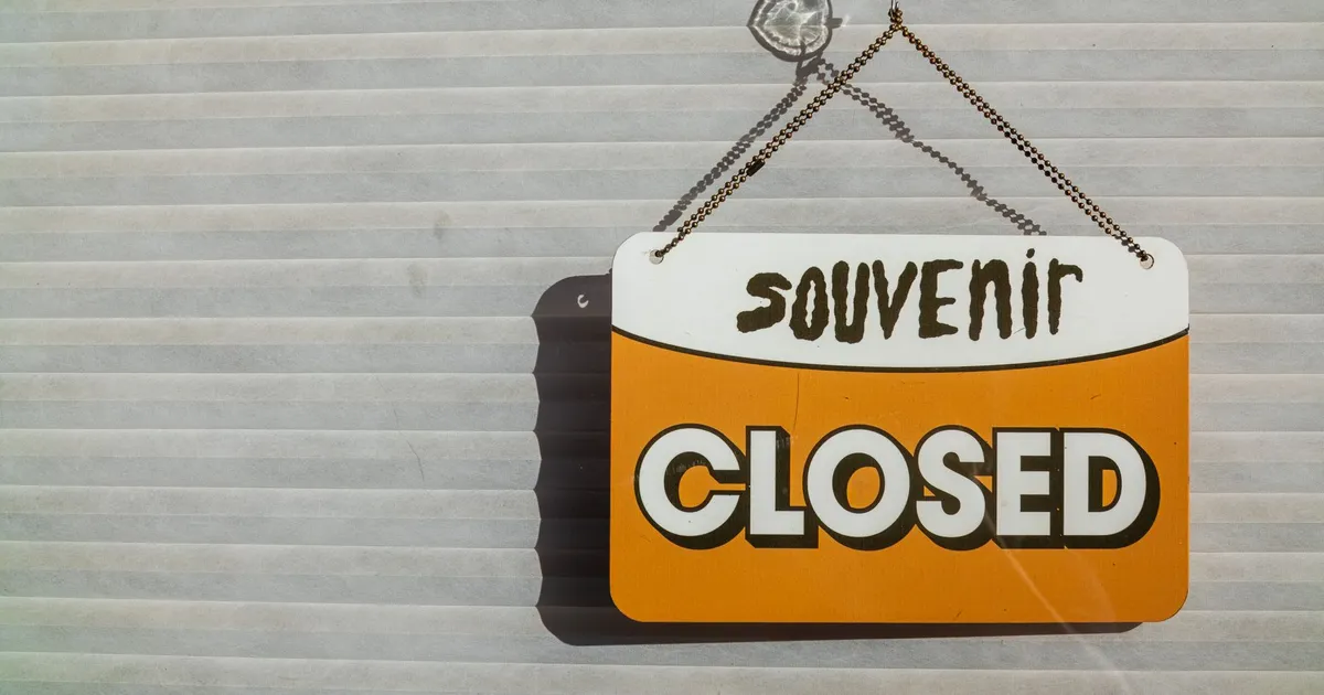 A 'Closed' sign for a souvenir shop hanging on a sunlit window.
