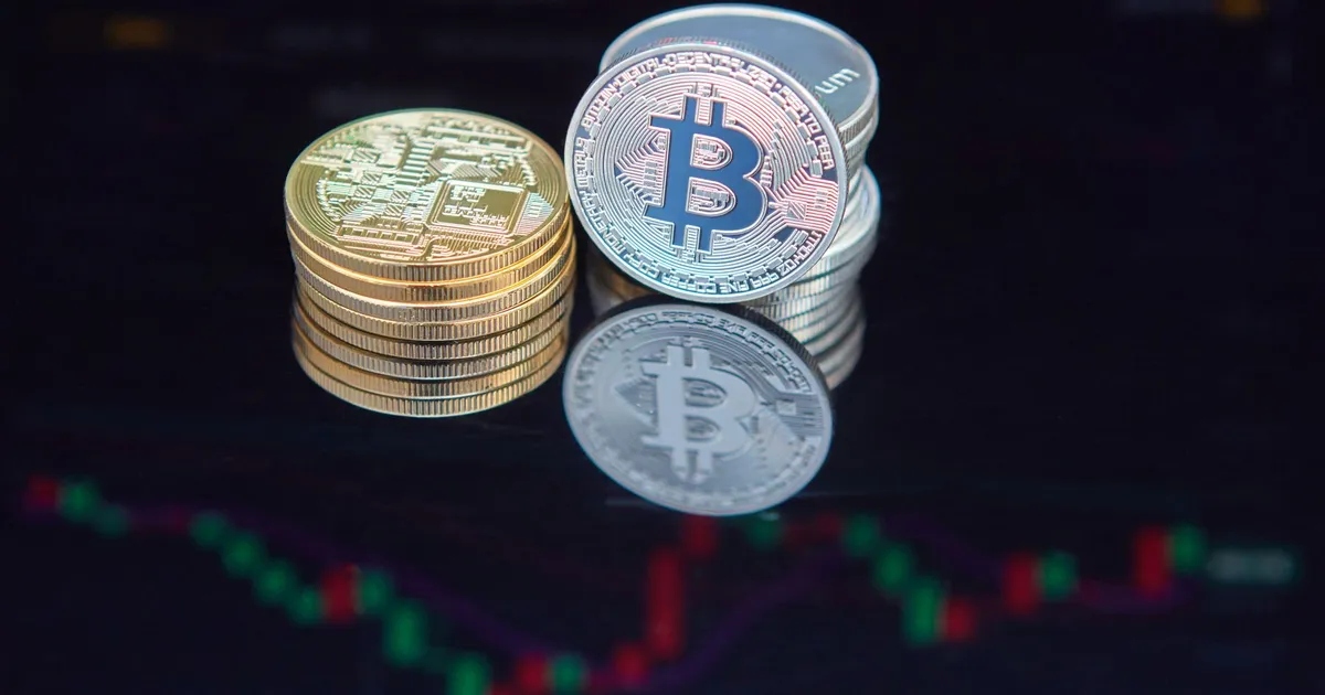 Close-up of bitcoin coins reflecting on a screen with financial market data, highlighting digital currency trend.