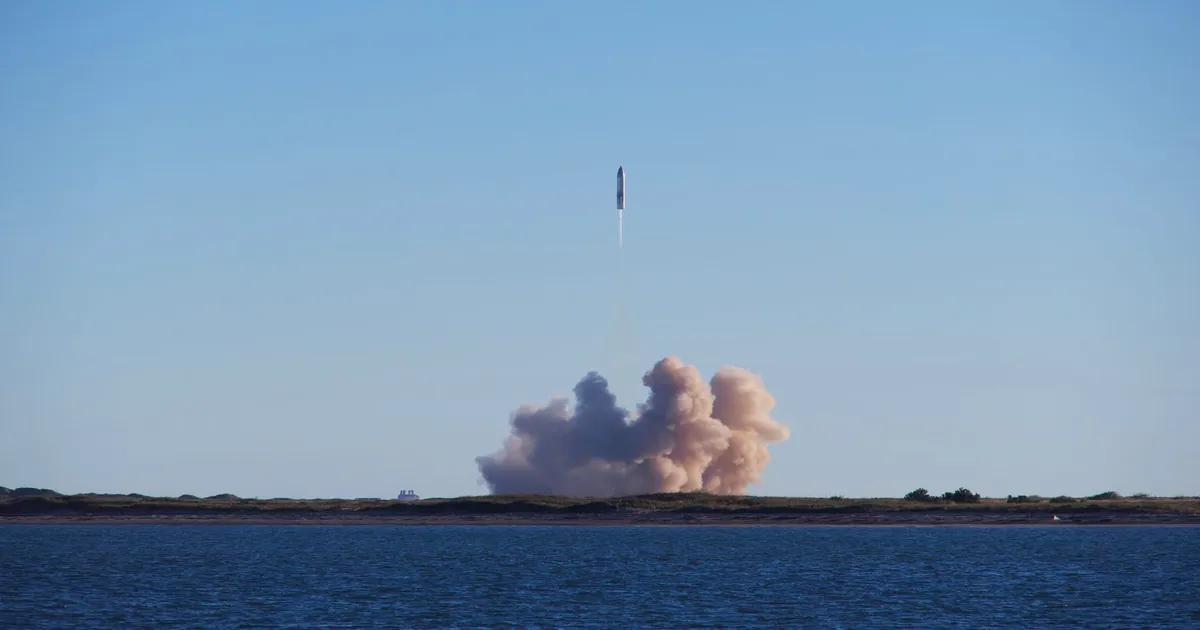 A rocket launch with smoke trails over South Padre Island, viewed across the ocean.