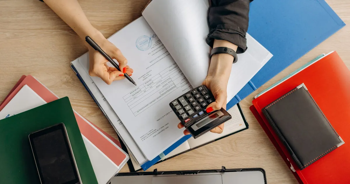 Accountant analyzing financial documents with a calculator on a desk, highlighting business tasks.
