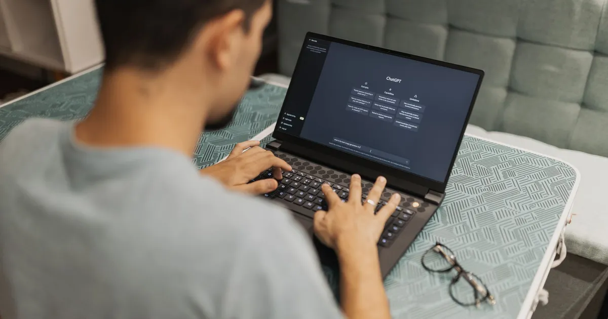 A man working on a laptop displaying ChatGPT's interface in an indoor setting.