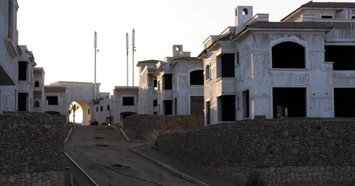 View of an unfinished residential area with buildings and stone walls during sunset.
