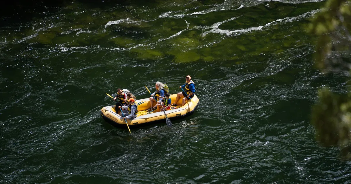 Family enjoying rafting adventure on Green River, Utah, in a yellow inflatable raft.
