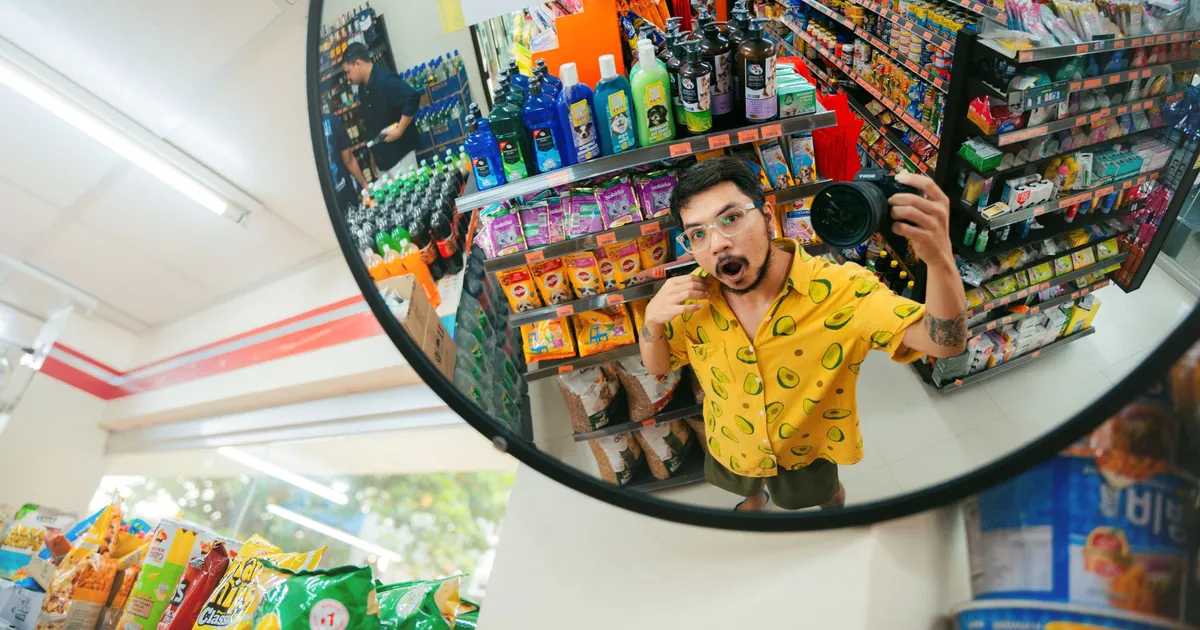Playful selfie reflection in a convenience store mirror capturing colorful aisles and products.