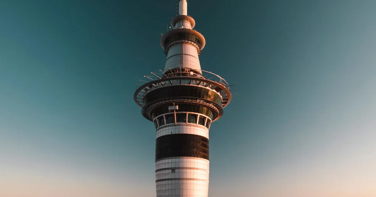 Photograph of the iconic Sky Tower in Auckland, New Zealand against a clear sky at sunset.