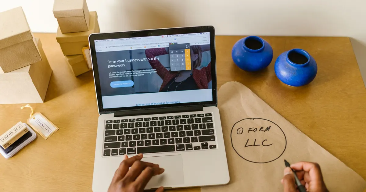 Workspace with laptop, packaging, and handwritten LLC notes, ideal for a small business startup scene.
