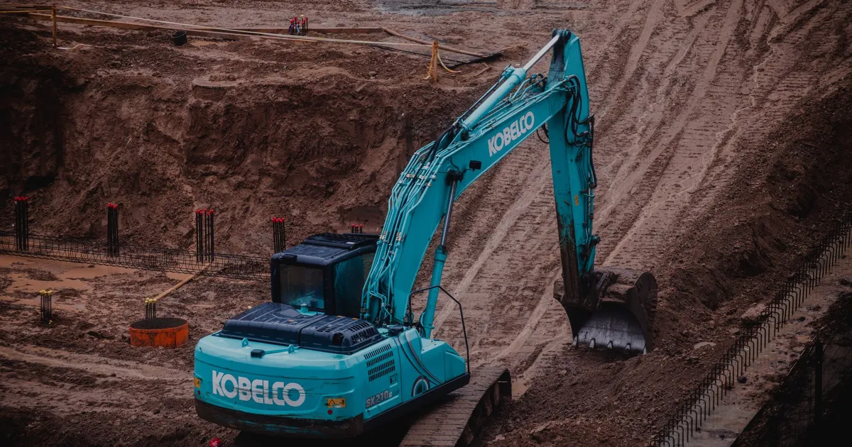 Blue excavator digging a pit at a construction site in Vilnius, Lithuania.