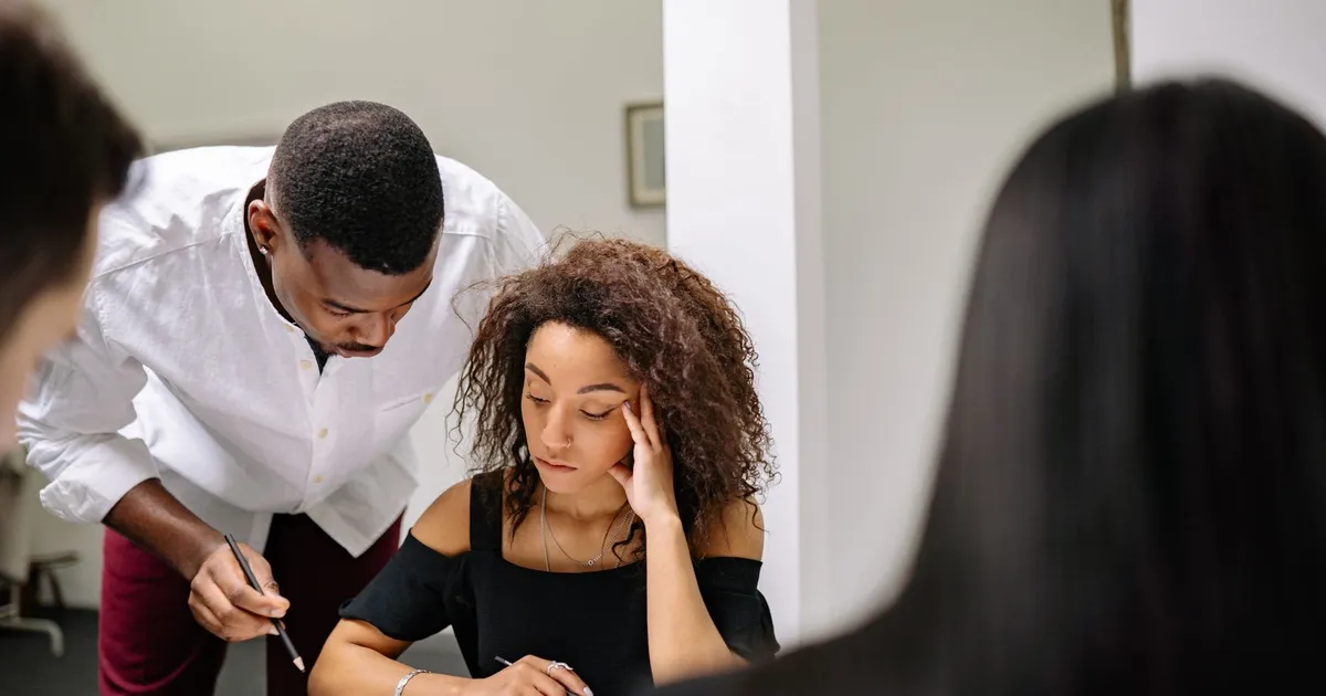 Businesswoman feeling stressed during a team meeting as colleagues assist.