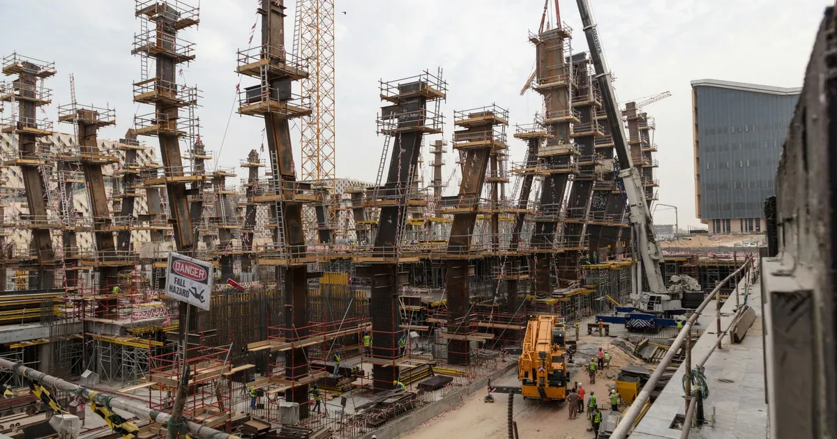 A bustling construction site with towering steel frameworks and cranes under a cloudy sky.