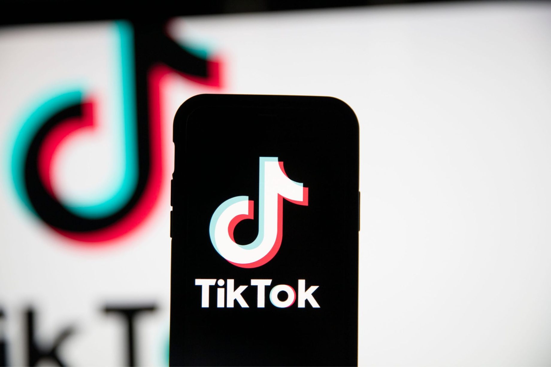 Smartphone displaying the TikTok logo in front of a larger TikTok logo