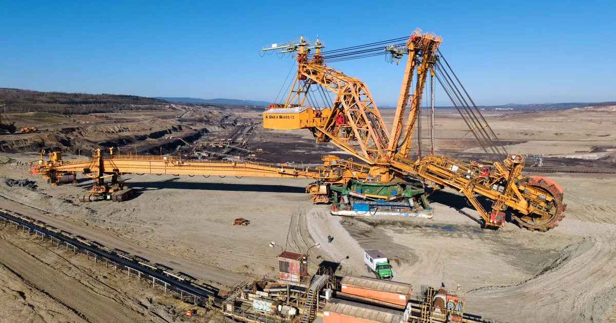 Aerial view of a giant excavator at work in a vast open-pit mining landscape.